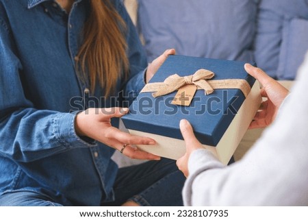 Closeup image of a couple women receiving and giving a gift box to each other