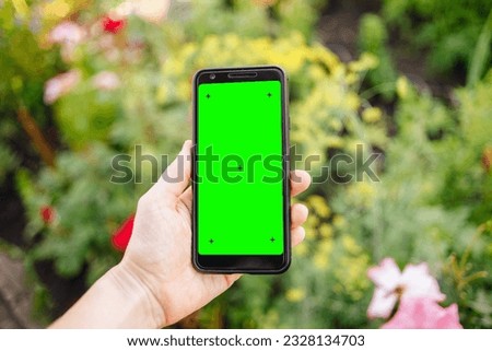 Woman holding smartphone with green screen outdoors, closeup. Gadget display with chroma key