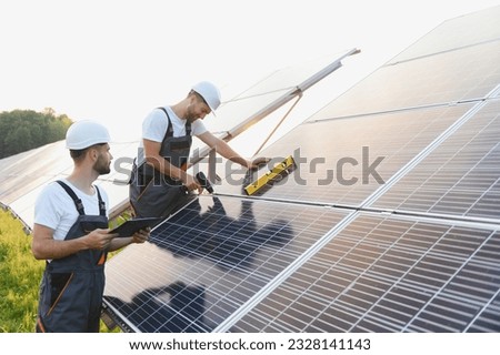 Engineering team working on checking and maintenance in solar power plant, Solar panel technician installing solar panels on roof on a sunny day. Royalty-Free Stock Photo #2328141143