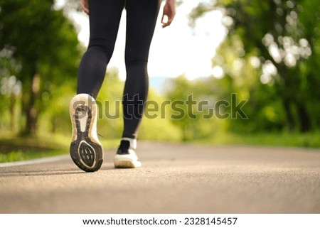 Sporty woman running and jogging in the park. Close up picture of running shoes on a path in the park.