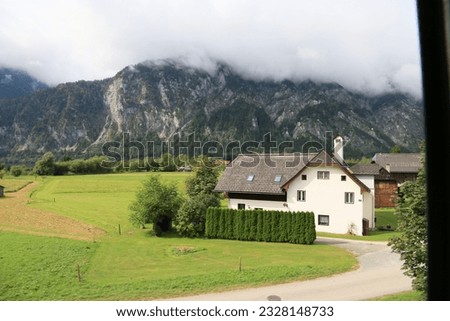 A green field with houses and mountains in the background