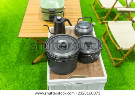 steel pot, chair,portable gas stove, bowl and vintage lanterns on outdoor wooden table in camping area
