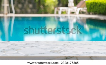 Empty table top and blurred swimming pool in tropical resort in summer for display or montage your products. Royalty-Free Stock Photo #2328175305