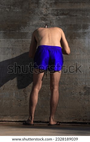 An unrecognizable man, seen from behind, in a swimsuit, bathing in a shower on the beach Royalty-Free Stock Photo #2328189039