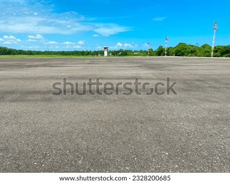 empty or quiet runway airport with lots of trees at noon against bright blue sky with clouds Royalty-Free Stock Photo #2328200685