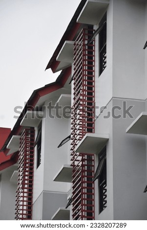 a photo of gray and red dormitory buildings that appear neatly lined up in the afternoon sun taken from a lower side angle in telkom university