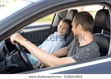 Dad sits with the child in the car and holds the steering wheel. The child is in the front seat. Leather interior in a black car Royalty-Free Stock Photo #2328214031