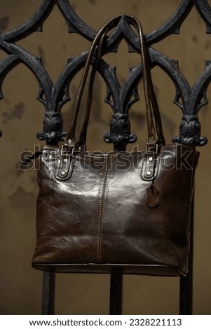 close-up photo of brown leather bag on a metal fence. outdoors photo