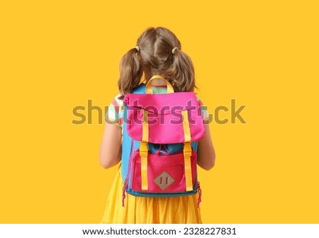 Cute little girl with backpack on yellow background, back view Royalty-Free Stock Photo #2328227831