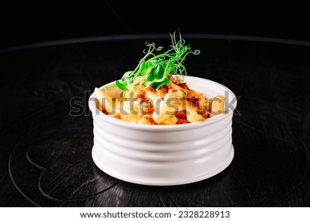 Salted French fries with bacon and cheese sause in white bowl on a wooden table