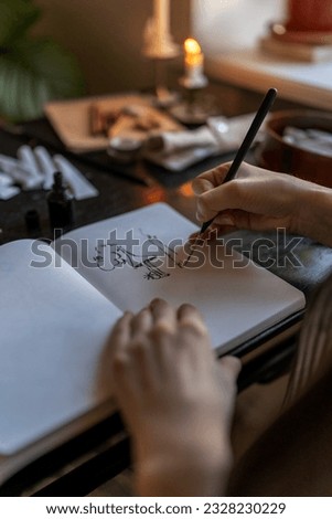 Closeup of artist holding fountain pen drawing with ink while sitting at table with sketchbook and painting tools, drawing at home, creating artwork. Creative people and inspiration concept Royalty-Free Stock Photo #2328230229