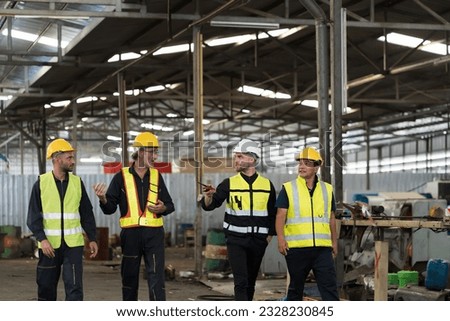 Group of male factory workers discussing of their work in industry factory, wearing safety uniform and helmet. Factory workers working in factory