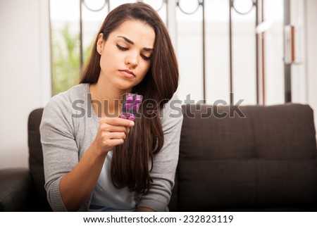 Pretty young Hispanic woman reading the label of some pills she is about to take