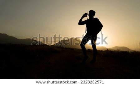 silhouette of mountaineer making phone call
