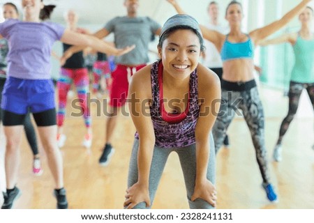 Portrait smiling woman resting with hands on knees in exercise class Royalty-Free Stock Photo #2328241131