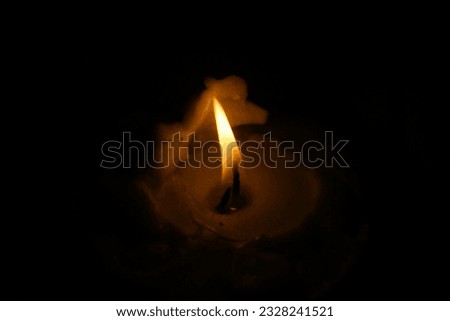 Close-up of a picture of a fire burning on a small candle in the dark during a power cut