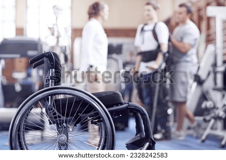 Man receiving physical therapy with wheelchair in foreground Royalty-Free Stock Photo #2328242583