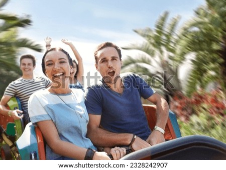 Young couple cheering on amusement park ride Royalty-Free Stock Photo #2328242907