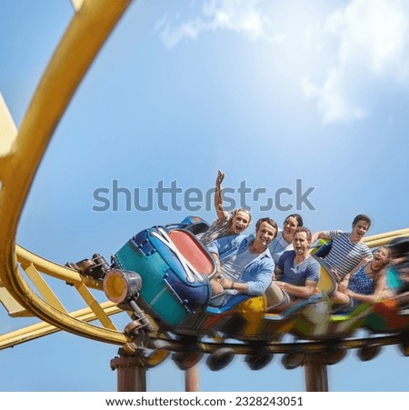 Cheering friends riding roller coaster at amusement park Royalty-Free Stock Photo #2328243051