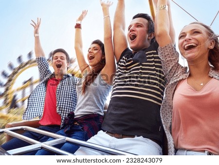Cheering friends riding amusement park ride Royalty-Free Stock Photo #2328243079