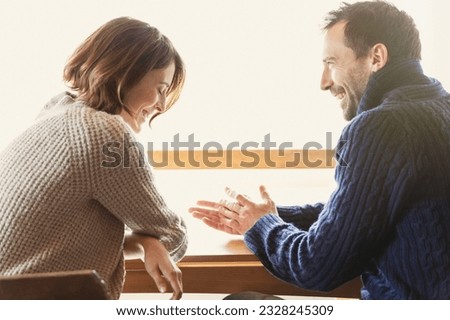 Laughing couple in sweaters at table Royalty-Free Stock Photo #2328245309