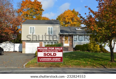 Real Estate sold (another success let us help you buy sell your next home) sign suburban high ranch home autumn day residential neighborhood blue sky clouds USA