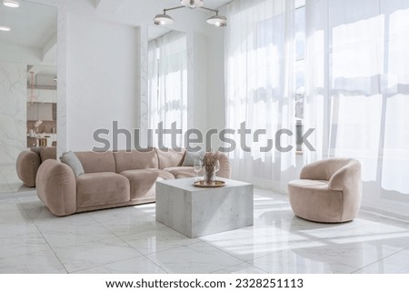 living room with soft beige furniture in a light luxury interior design of a modern apartment in a minimalist style with marble trim and huge windows. daylight inside. Royalty-Free Stock Photo #2328251113