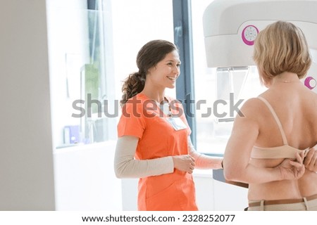 Nurse helping patient prepare for mammogram
