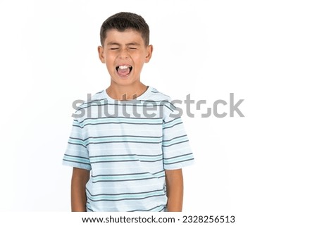 Little hispanic kid boy wearing striped T-shirt sticking tongue out happy with funny expression. Emotion concept. Royalty-Free Stock Photo #2328256513