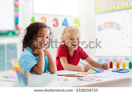 Kids go back to school. Interracial group of children of mixed age in classroom. Students learn to read and write. Preschooler or kindergarten kid with teacher. Child learning letters with flash cards Royalty-Free Stock Photo #2328258725