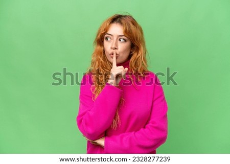 Young caucasian woman isolated on green screen chroma key background showing a sign of silence gesture putting finger in mouth