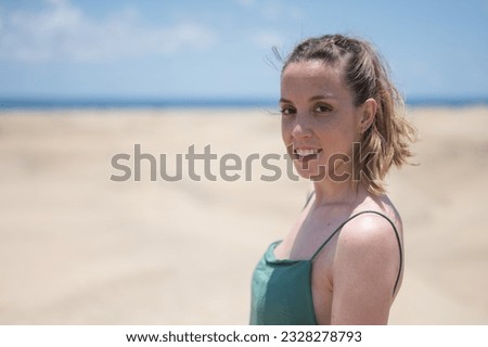 Portrait of a blonde young girl in green dress on the beach dunes