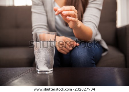 Closeup of a young brunette watching an antacid dissolve before drinking
