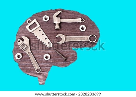 Brain-shaped figure filled with miniature replicas of hand tools such as hammer, hand saw, wrenches and fasteners. Connection between intellect, problem-solving and practical skills.