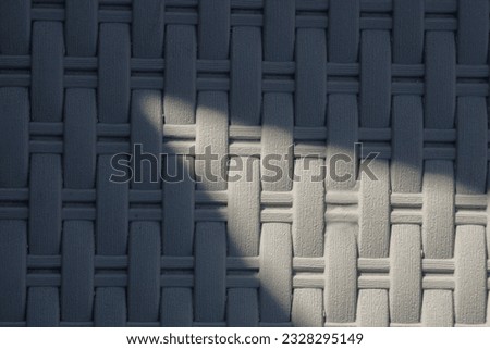 The unique textured chair in gray is photographed from above when it is exposed to sunlight and there is a dark shadow created by the objects around it