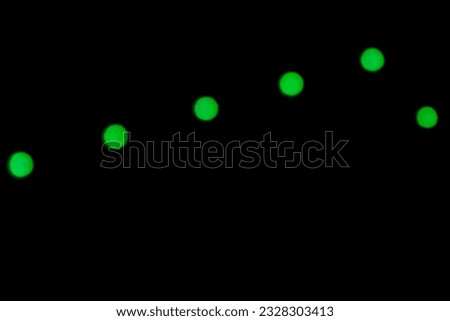 The bright green lights forming a striped pattern come from a nightlight photographed in the dark against a blurred background