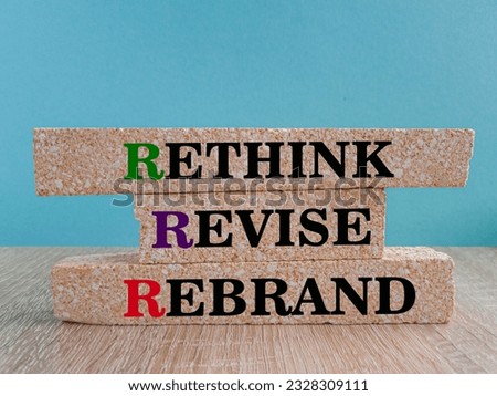 Rethink, revise, rebrand symbol. Business management branding concept of rethink revise and rebrand words on brick blocks. Wooden table, blue background.