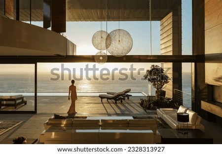 Woman in modern house overlooking ocean Royalty-Free Stock Photo #2328313927