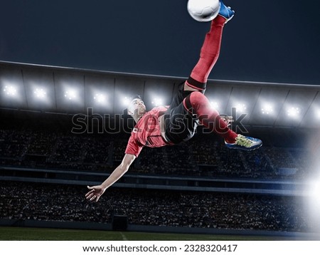 Soccer player kicking ball in mid-air on field Royalty-Free Stock Photo #2328320417
