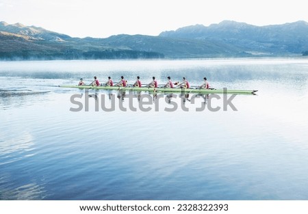 Rowing team rowing scull on lake Royalty-Free Stock Photo #2328322393