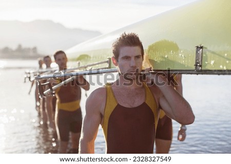 Rowing team carrying scull out of lake Royalty-Free Stock Photo #2328327549