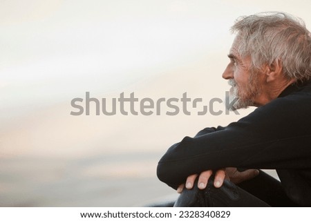 Older surfer sitting on beach Royalty-Free Stock Photo #2328340829