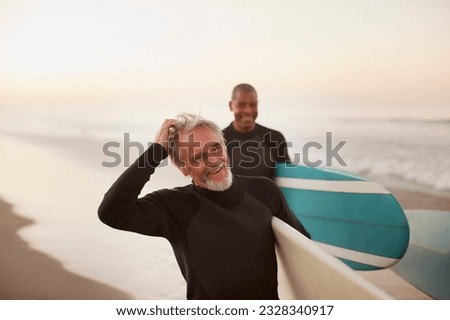 Older surfers carrying boards on beach Royalty-Free Stock Photo #2328340917