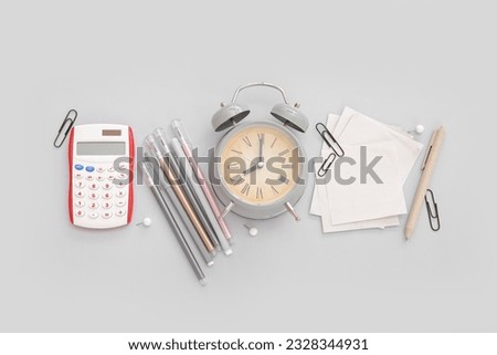 Alarm clock with calculator and different stationery on grey background