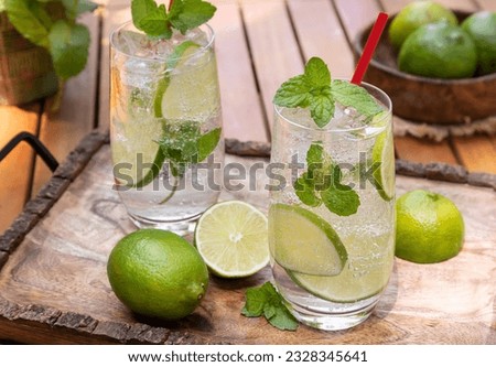 Mojito cocktail with lime slices and mint leaves outdoors on wooden tray 