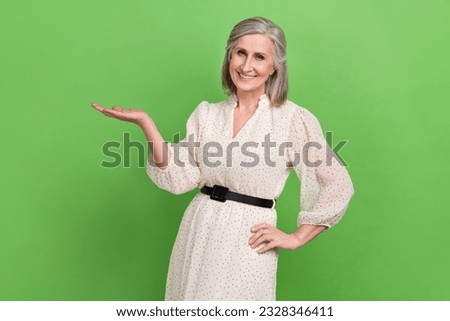 Portrait of good mood woman with bob hairdo wear stylish dress arm demonstrate offer empty space isolated on green color background