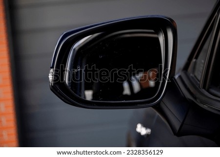A portrait of a sideview mirror with an emblem of the pedestrian and other vehicle detection safety feature of a car, which lights up when there is somekind of danger of having an accident.