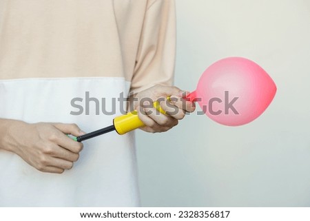 Blowing pink balloon by hand air pump, inflates  air to balloon Concept, children play, toy and equipment to play fun games or prepare party.                                                         Royalty-Free Stock Photo #2328356817