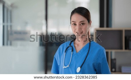 Portrait young and attractive confident Asian female doctor wearing a blue gown. Successful doctor career concept.