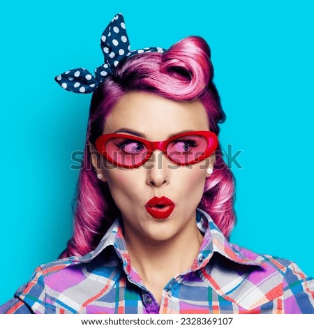 Excited surprised woman. Pinup girl  in red glasses looking sideways. Purple head model at retro fashion and vintage concept. Aqua blue background. Square composition image.